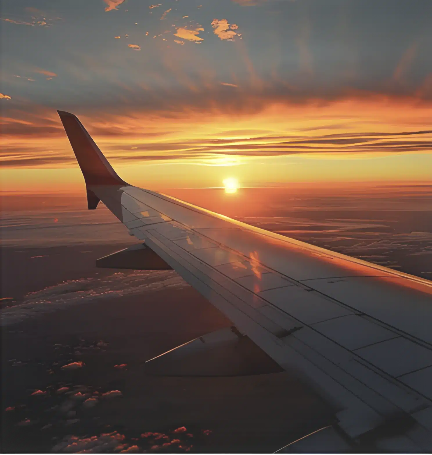a breathtaking view from an airplane window, showcasing a stunning sunset amidst vibrant clouds.
