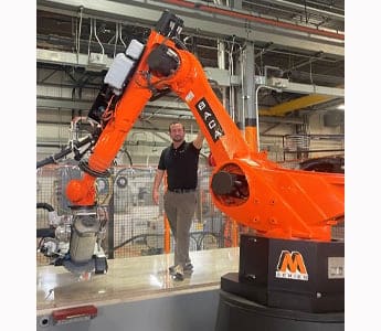 Tony Russo, VP of Sales at BACA Systems, standing on cutting table with Robo SawJet M Series 240 machine